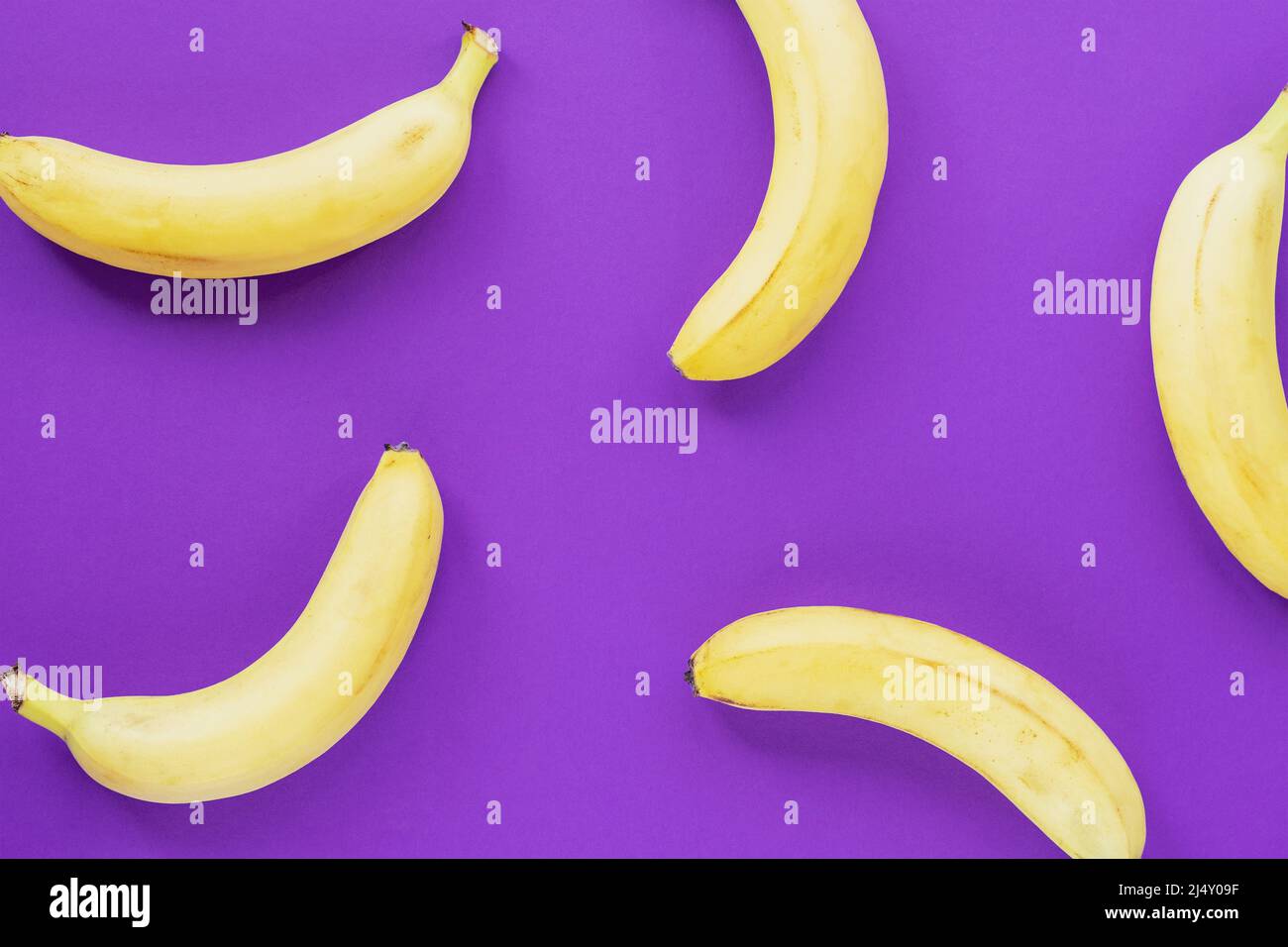 Bananes mûres jaunes sur fond violet, texture Banque D'Images