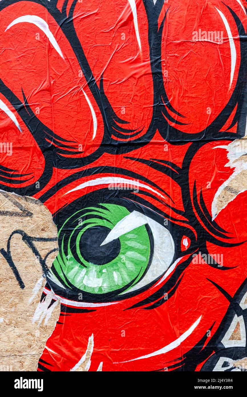 Affiche, partiellement déchirée, représentant un œil vert dans le creux d'un poing rouge. Bruxelles Banque D'Images