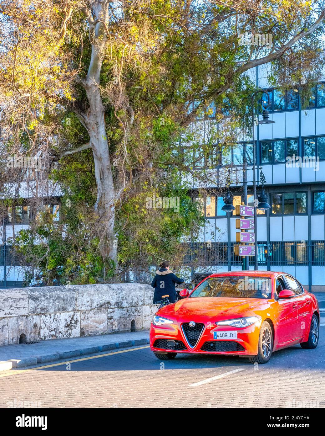 Une voiture rouge Alfa Romeo se trouve dans une rue de la ville. Un arbre et un immeuble d'appartements sont vus en arrière-plan. La vieille ville est une attraction touristique majeure. Banque D'Images