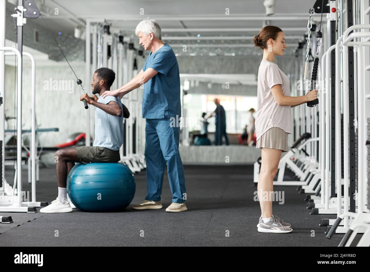 Portrait complet des personnes utilisant des machines de physiothérapie à la salle de gym dans la clinique de réadaptation Banque D'Images