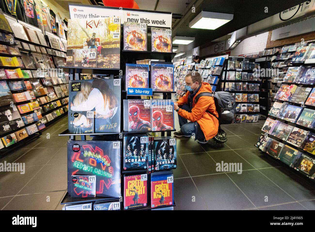 COVID shopping UK; Homme magasiner pendant la pandémie de COVID portant un masque et achetant des DVD à l'intérieur d'un magasin pendant la pandémie de COVID 19, Cambridge UK Banque D'Images