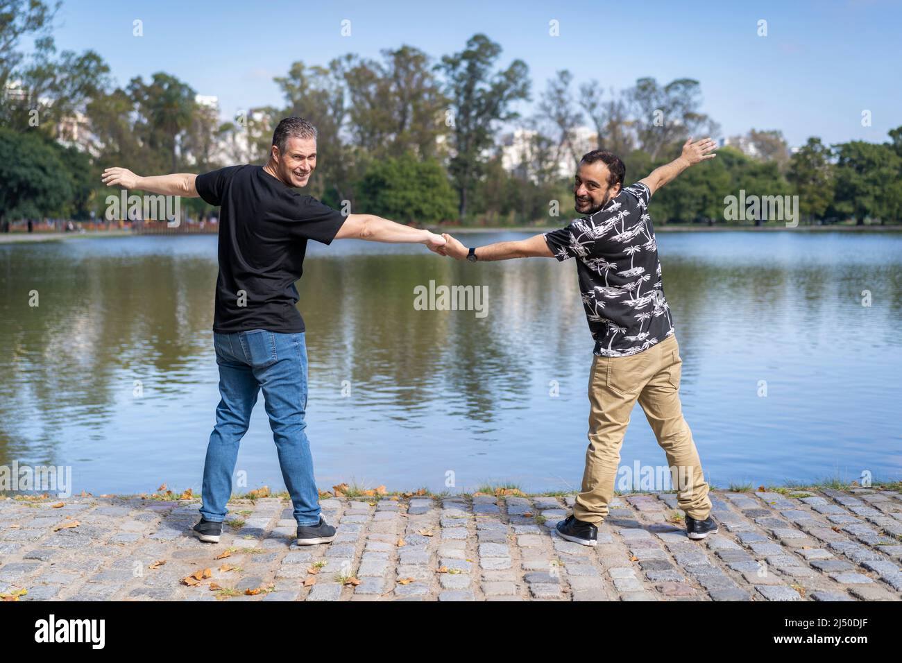 Homosexuel mature couple blanc mâle tenant les mains dos à dos à un lac Banque D'Images
