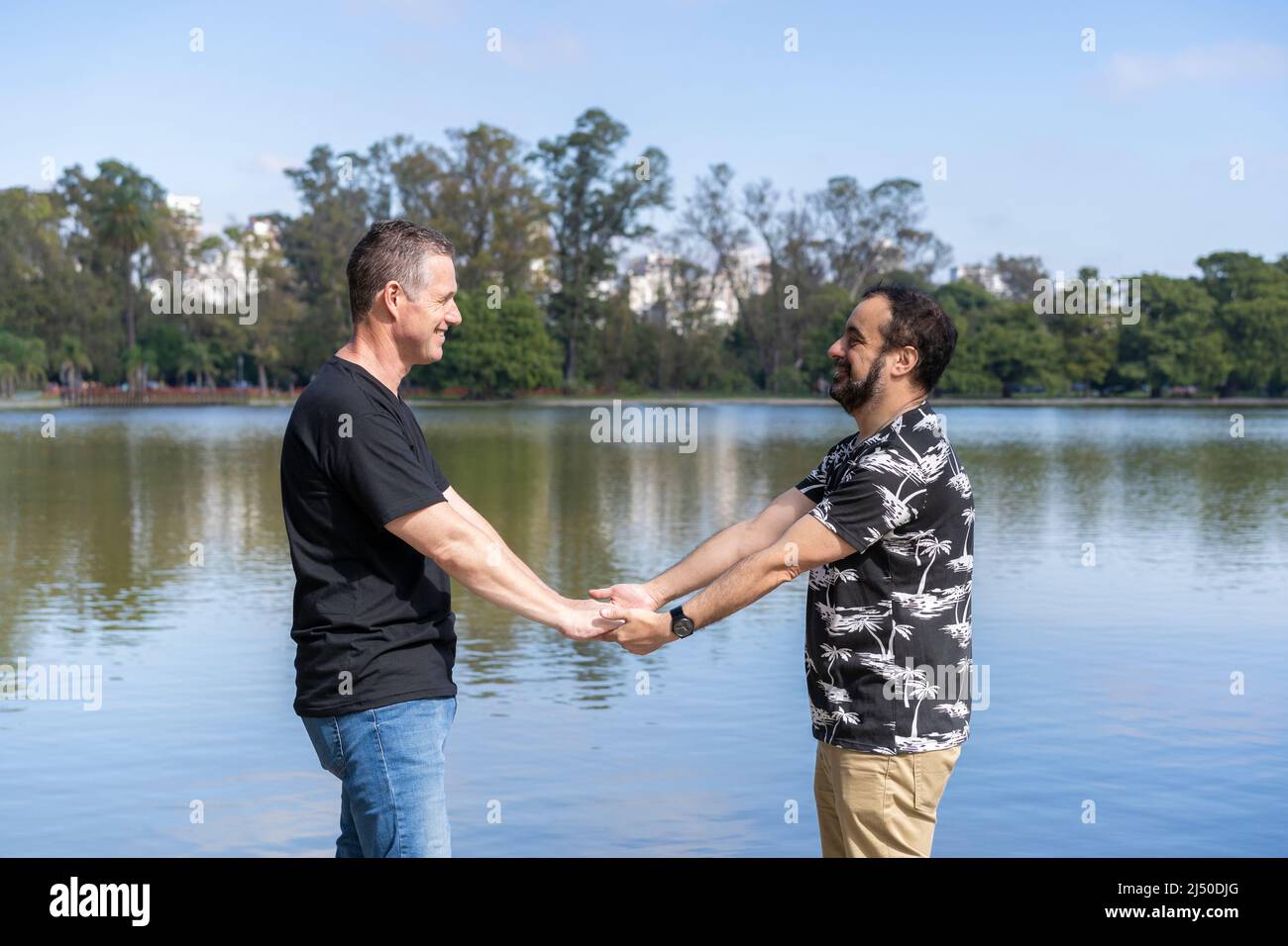 Homosexuel mature couple blanc mâle tenant les mains dos à dos à un lac Banque D'Images