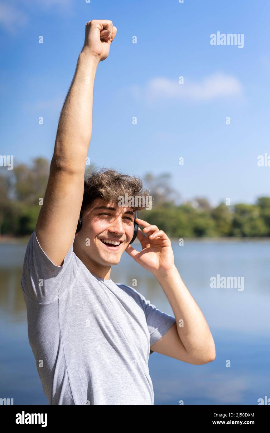 Jeune homme écoutant de la musique en extérieur avec un casque bluetooth. Expression du bonheur, attitude gagnante. Banque D'Images