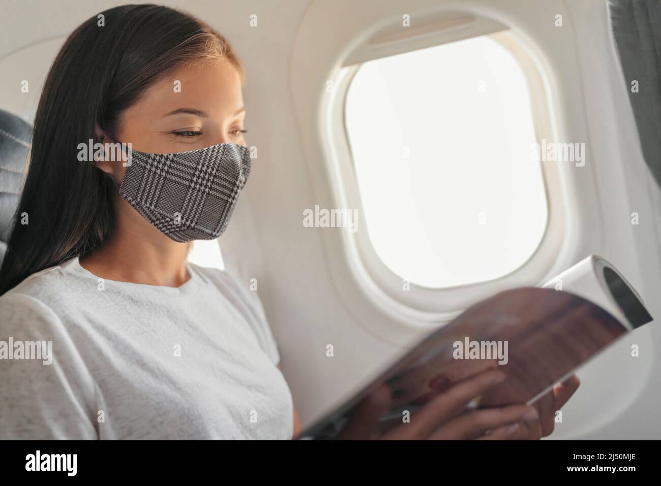 Le coronavirus voyage covid pendant une pandémie asiatique femme portant un masque facial dans la cabine à l'intérieur de l'avion pendant le magazine de lecture de vol sur le siège de la fenêtre passager Banque D'Images Le coronavirus voyage covid pendant une pandémie asiatique femme portant un masque facial dans la cabine à l'intérieur de l'avion pendant le magazine de lecture de vol sur le siège de la fenêtre passager Banque D'Images