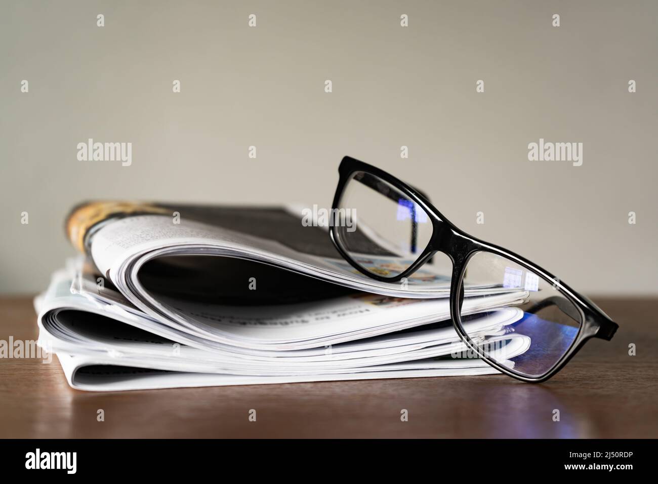Lunettes bleues bloquant la lumière sur la pile de journaux Banque D'Images