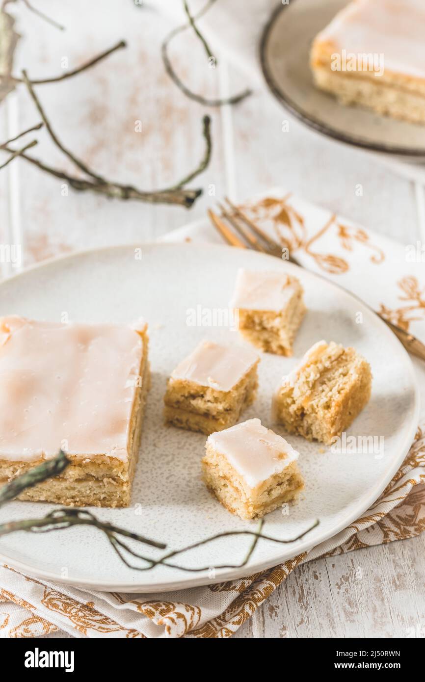 Morceaux de tarte aux pommes couverte avec glaçage au sucre sur fond de bois blanc. Concept de couleur harmonieuse dans les tons beige. Verticale. Banque D'Images