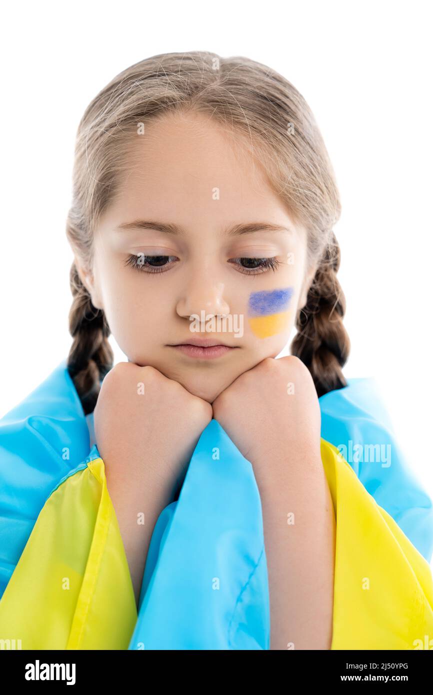 fille frustrée couverte d'un drapeau ukrainien tenant les mains près du visage isolé sur blanc Banque D'Images