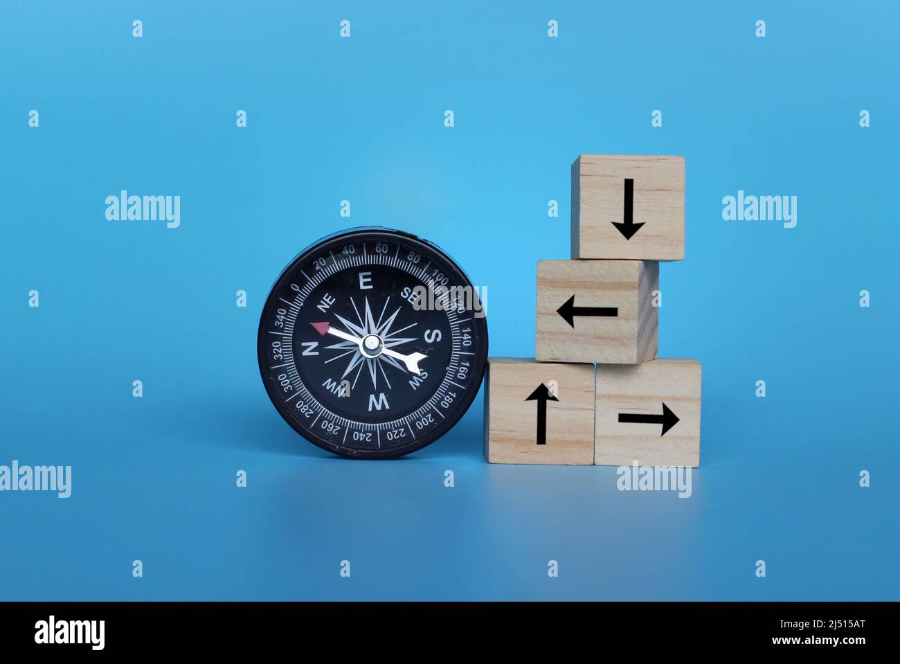 Compas et cubes en bois avec flèche sur fond bleu. Recherche de direction, concept de guidage Banque D'Images