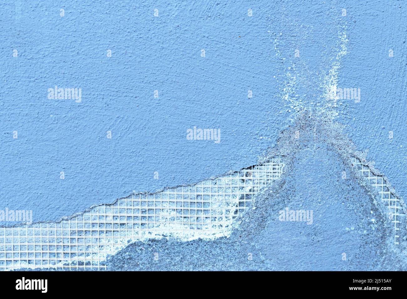 Mur en béton bleu avec grille métallique soudée montrant des pièces cassées Banque D'Images