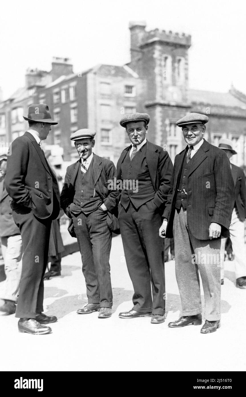 Un groupe de quatre hommes montrant les modes du 1930s, avec des chapeaux plats et des costumes. Banque D'Images