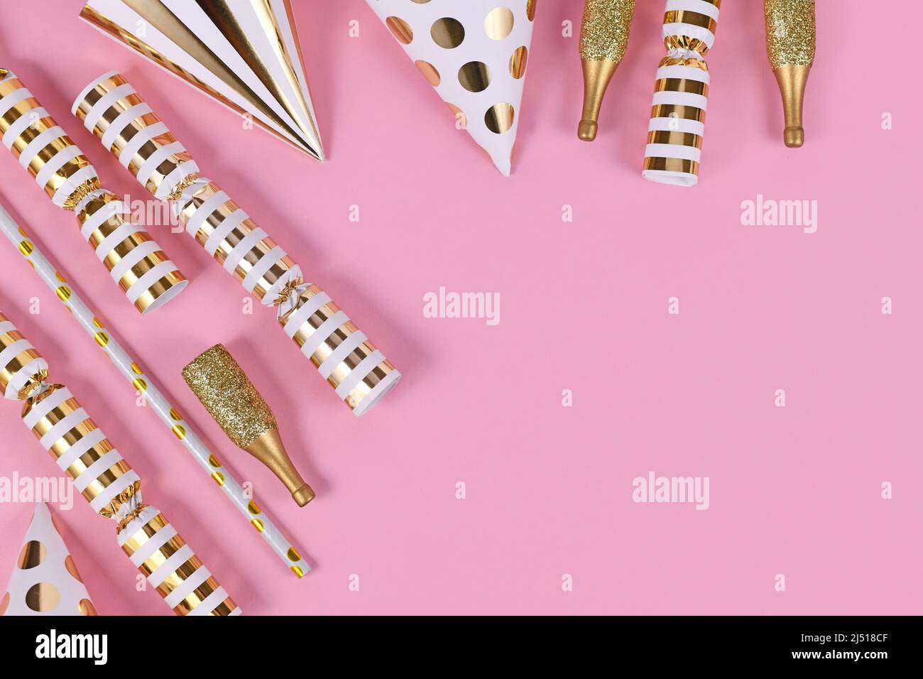 Des objets de fête d'or comme des chapeaux, des confettis et des cadeaux sur fond rose Banque D'Images Des objets de fête d'or comme des chapeaux, des confettis et des cadeaux sur fond rose Banque D'Images