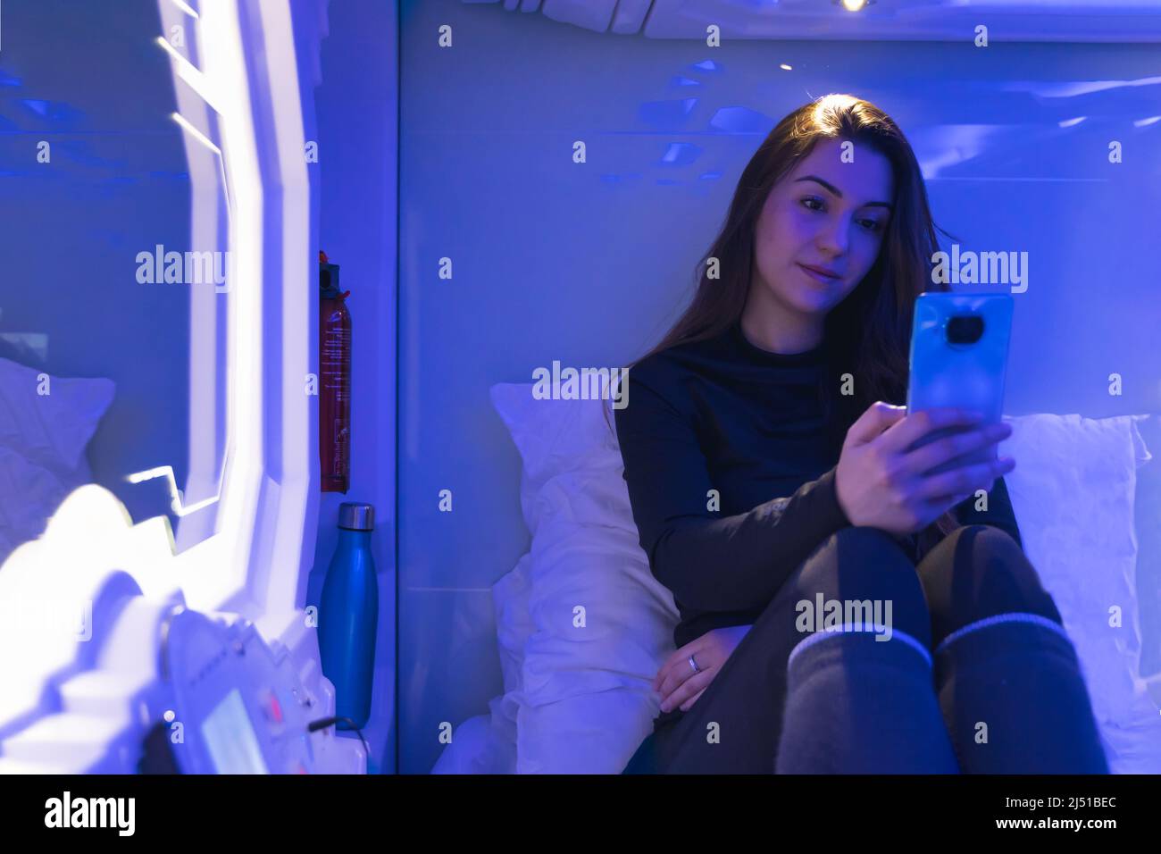 femme en capsule la nuit avec le téléphone Banque D'Images