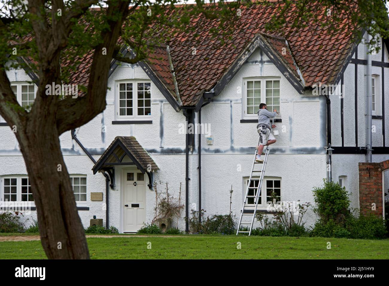 Jeune homme peint maison à colombages dans le village d'Askham Richard, North Yorkshire, Angleterre Banque D'Images