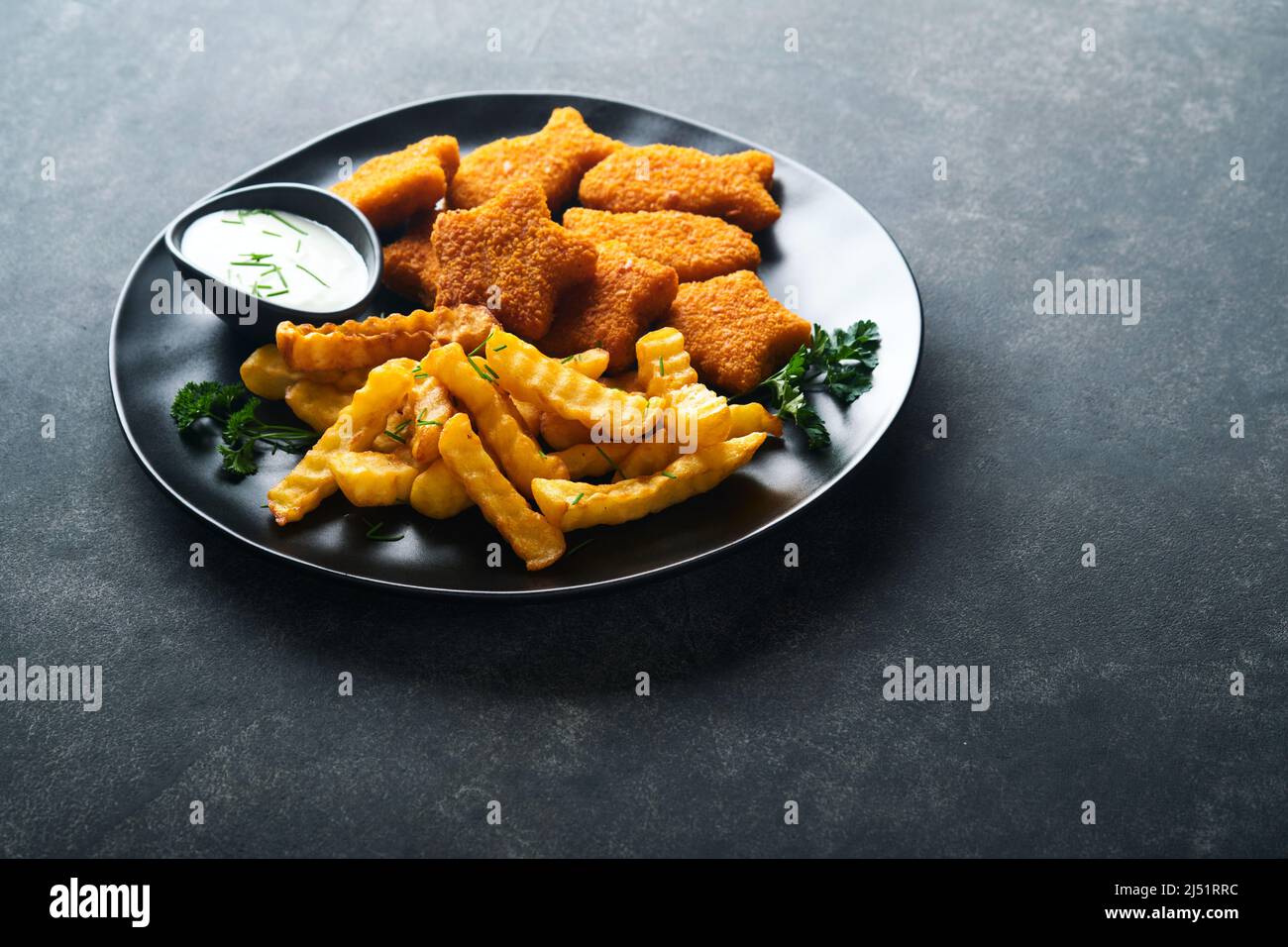 Fish Chips, restauration rapide britannique. Bâtonnets de poisson avec frites sur plaque noire sur fond de table noire. Cuisine traditionnelle britannique authentique ou Banque D'Images
