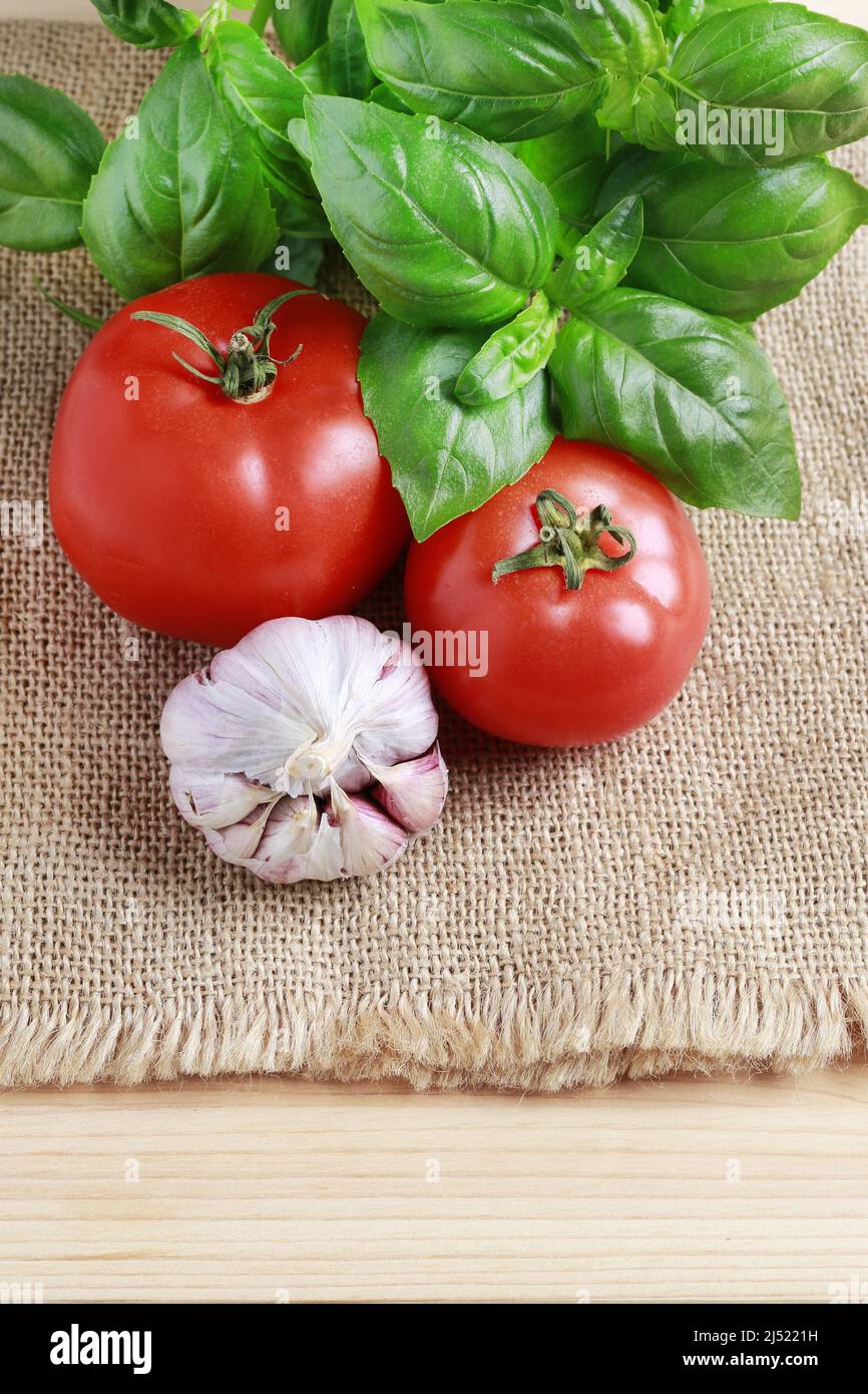 Tomates, ail et basilic plante sur fond de sac de jute. Une alimentation saine Banque D'Images