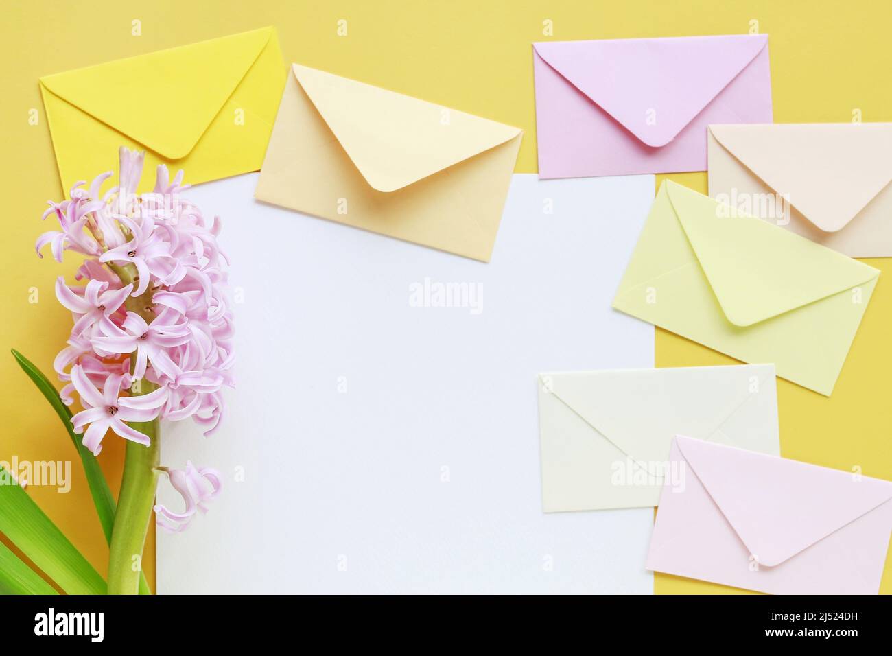 Enveloppes colorées et fleurs en jacinthe sur fond jaune, espace de copie. Banque D'Images