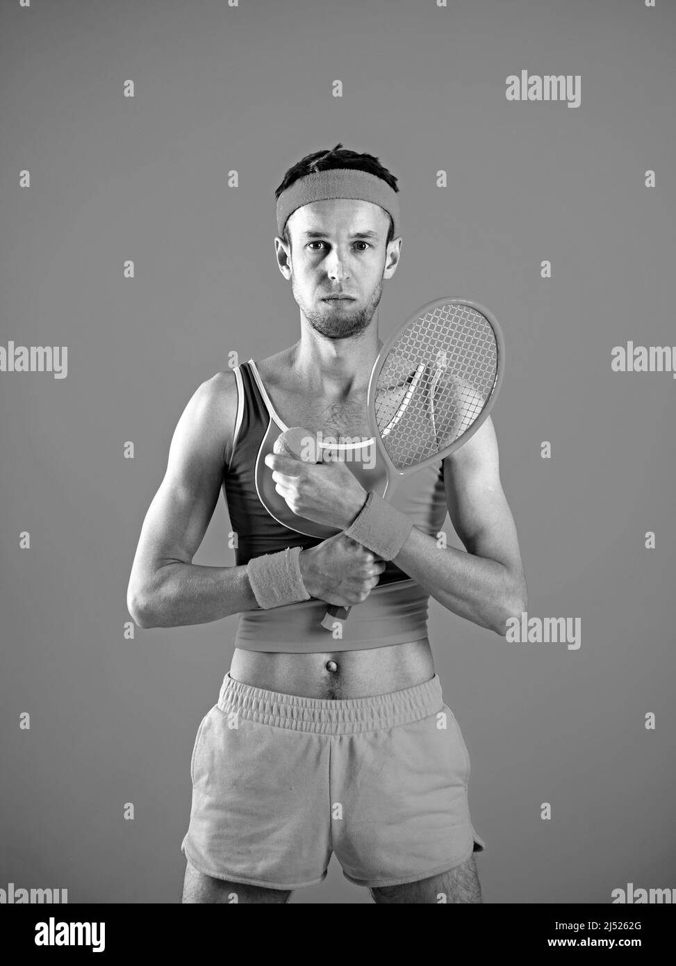 Jeune homme attrayant en costume décontracté tenant une raquette et un ballon de tennis Banque D'Images