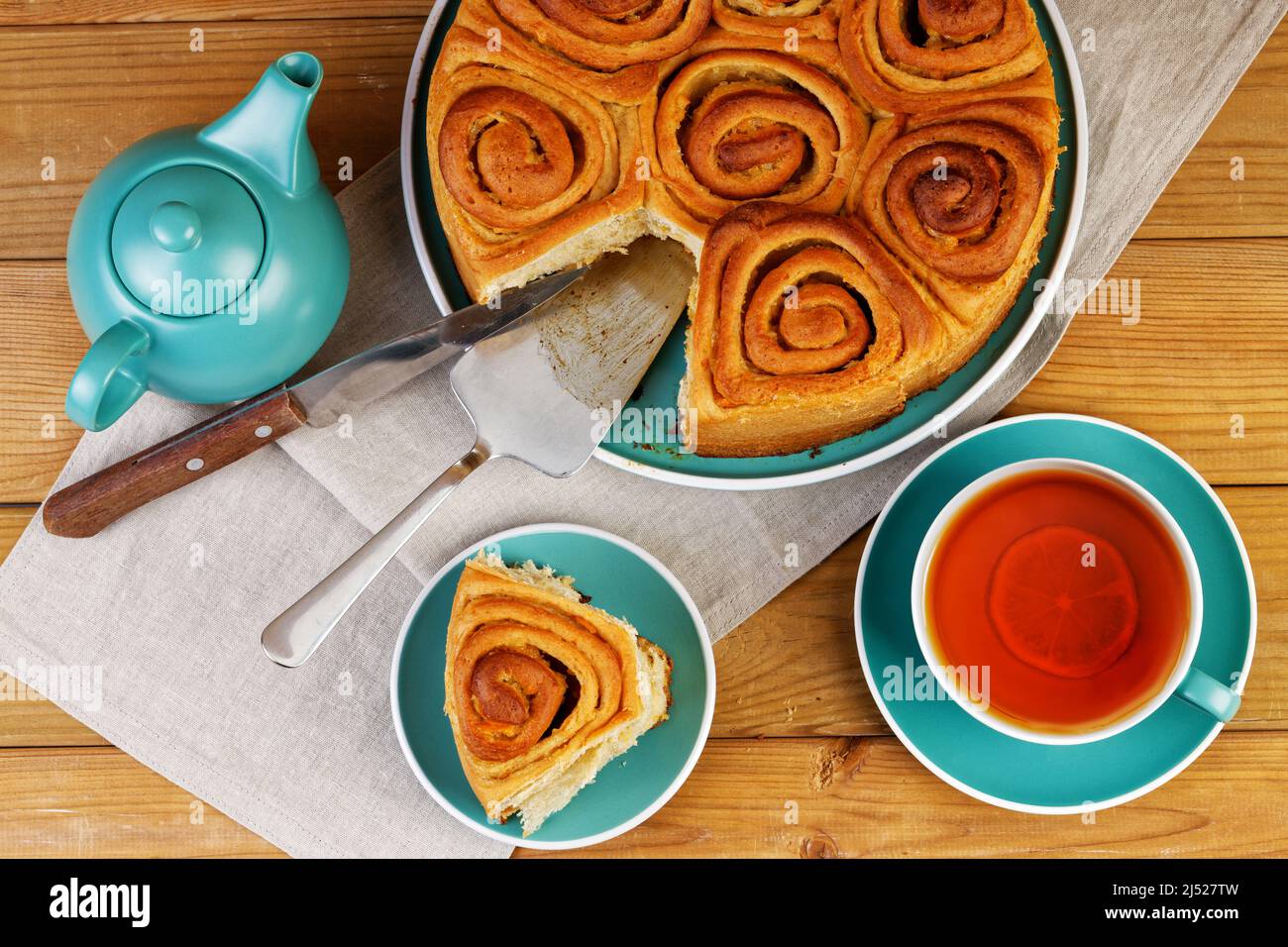 Petits pains à la cannelle faits maison de pâte à levure et une tasse de thé sur une table en bois. Vue de dessus. Banque D'Images Petits pains à la cannelle faits maison de pâte à levure et une tasse de thé sur une table en bois. Vue de dessus. Banque D'Images