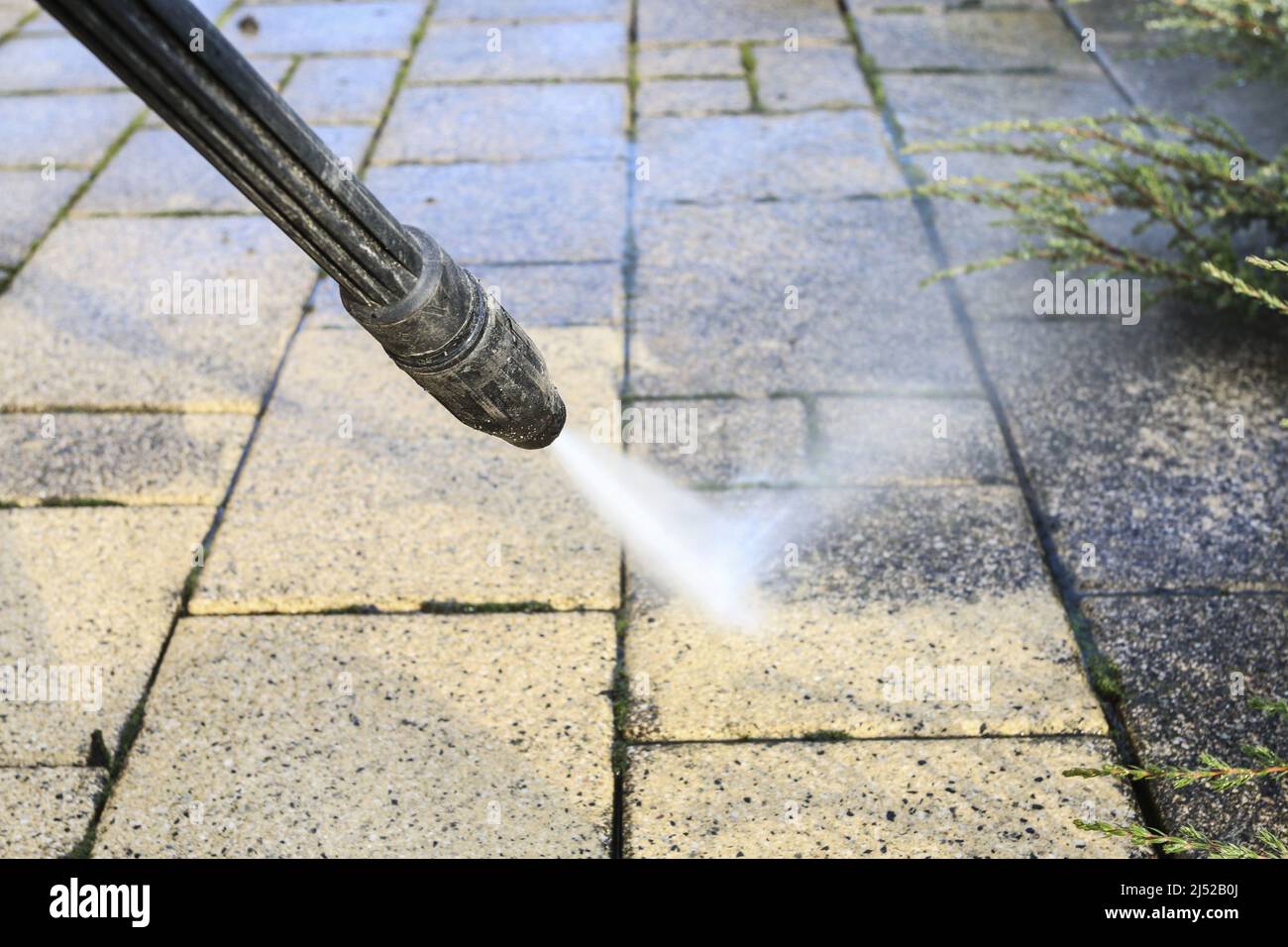 Nettoyage des pavés sales dans le jardin à l'aide d'un nettoyeur haute pression. Travailleur à domicile Banque D'Images