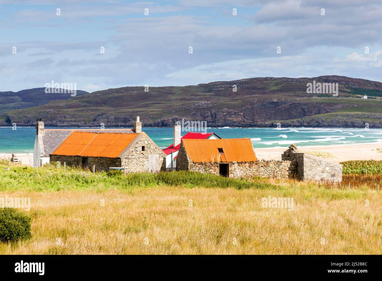 Un petit groupe de vieux bâtiments de ferme donnent sur une grande plage de sable déserte et sur une mer turquoise brillante à la baie de Torrisdale, par une journée ensoleillée. Banque D'Images