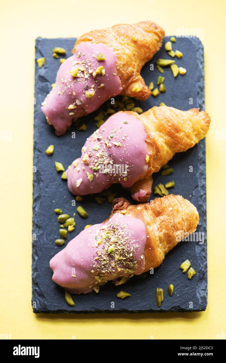 Mini-croissants au chocolat rubis et pistaches sur un plateau en ardoise. Vue surharée. Banque D'Images
