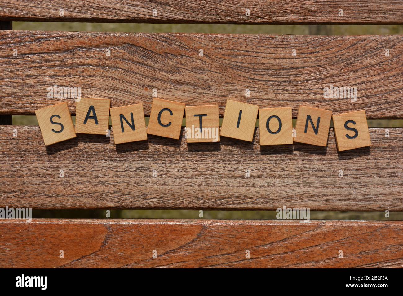 Sanctions, mot en lettres de l'alphabet de bois isolées sur fond de lattes de bois Banque D'Images