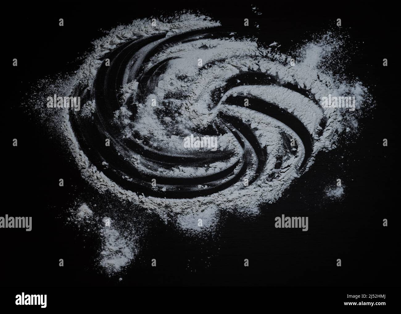 Fond noir parsemé de farine en forme de bulle, farine étalée, table de cuisson, pâte à rouler. Préparation de la cuisson, vue de dessus isolée sur Banque D'Images