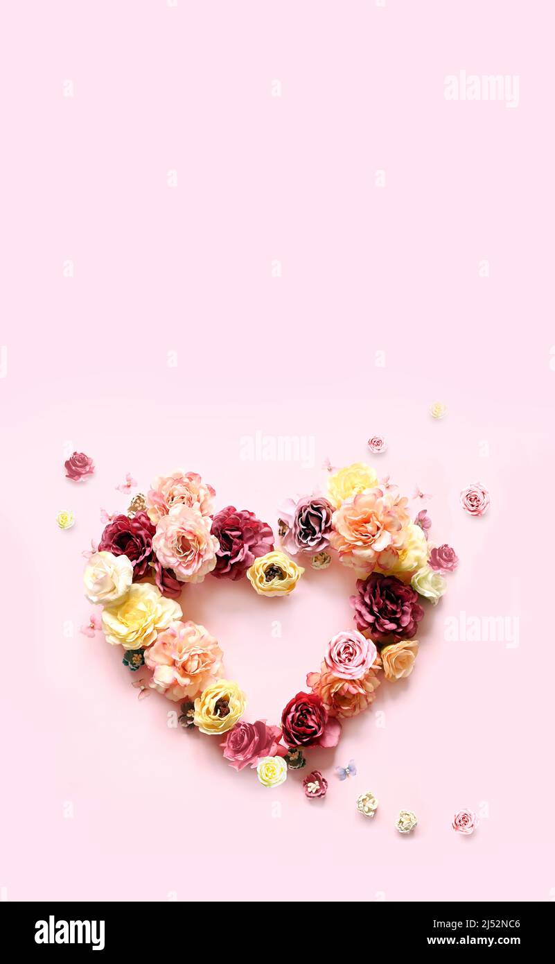 Bonne fête des mères et des Valentines. Bouquet de roses assorties colorées en forme de coeur sur fond rose et papillon. Concept de vacances Banque D'Images