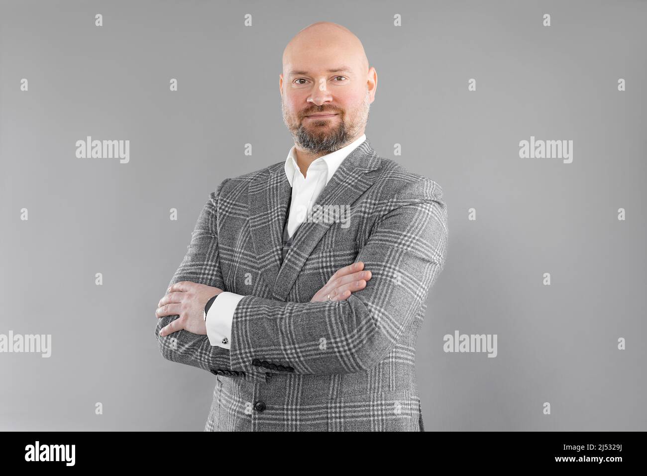 Portrait d'un homme d'affaires souriant d'âge moyen avec une veste à carreaux gris, une veste, une chemise blanche, debout avec des bras croisés. Banque D'Images