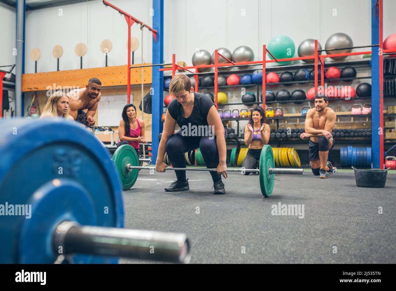 Une femme prête à faire de l'haltérophilie pendant que ses amis de gym l'applaudissent Banque D'Images