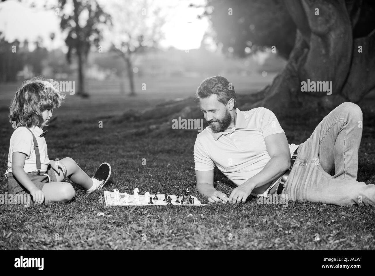 Le père joue aux échecs avec son fils. Famille en extérieur. Un petit garçon joue aux échecs avec un parent. Développement cognitif. Jeu intellectuel pour enfants. Enfants intelligents. Banque D'Images