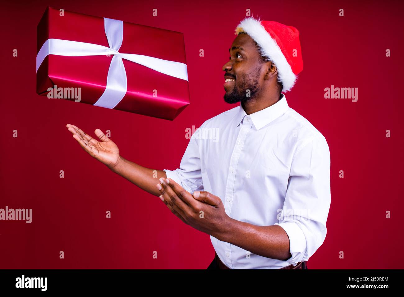 homme brésilien porte le port de la tête du père noël isolé sur fond rouge Banque D'Images