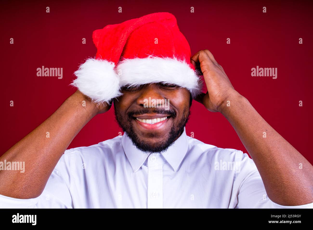 homme brésilien porte le port de la tête du père noël isolé sur fond rouge Banque D'Images