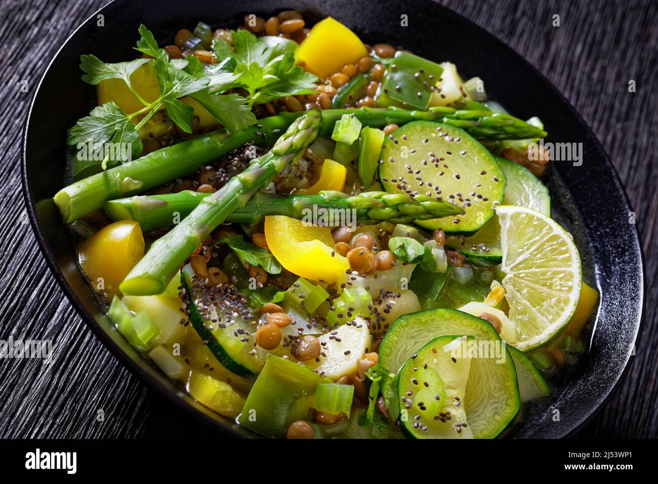 soupe verte alcaline à faible teneur en calories chargée de légumes de  printemps, de lentilles vertes, de graines de chia et d'herbes dans un bol  noir sur une table en bois sombre,