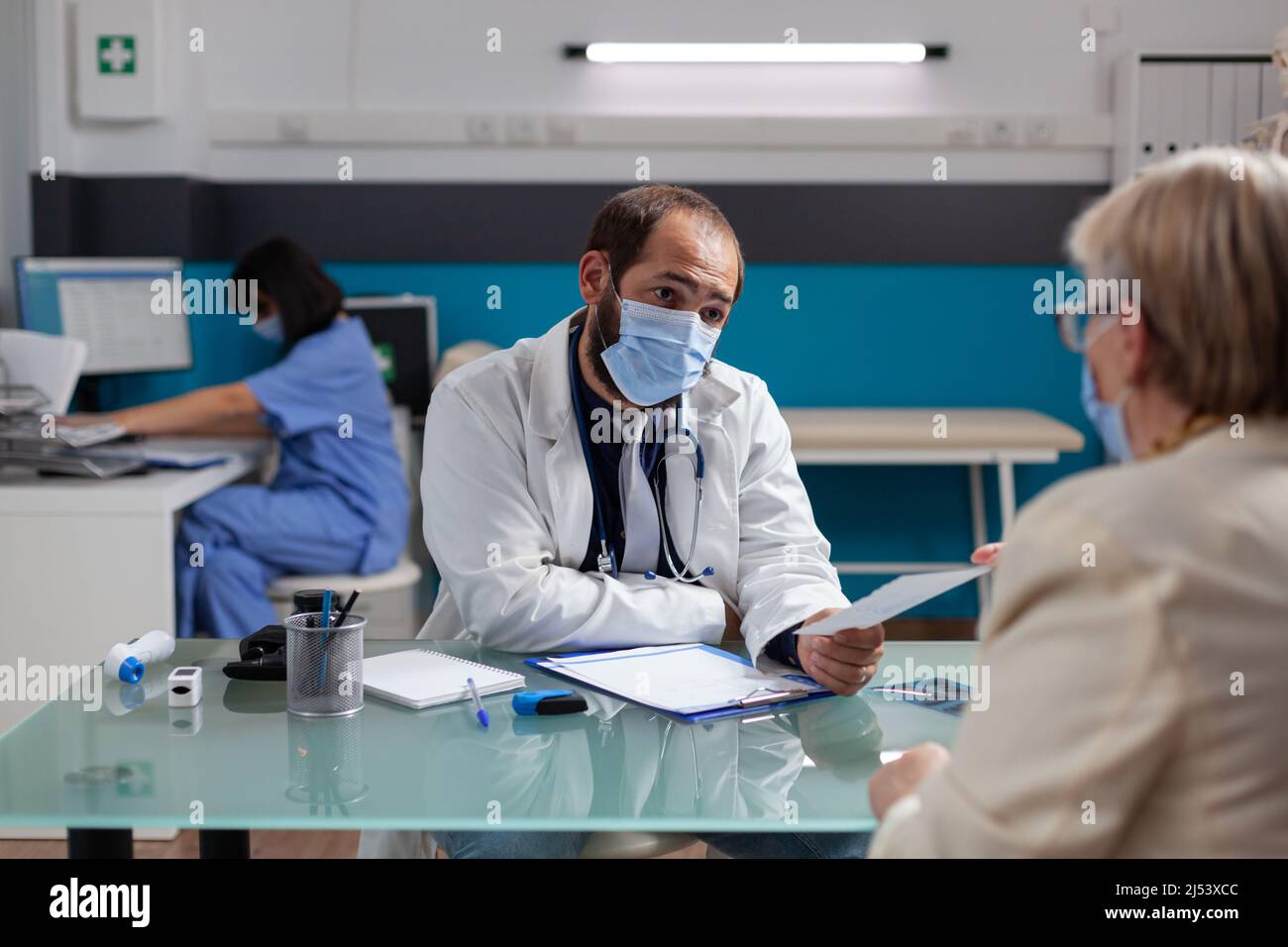 Spécialiste donnant du papier d'ordonnance au pensionné à son rendez-vous, après consultation médicale pendant une pandémie. Document de vérification de la détention de Medic pour donner le traitement à la personne à la retraite. Banque D'Images