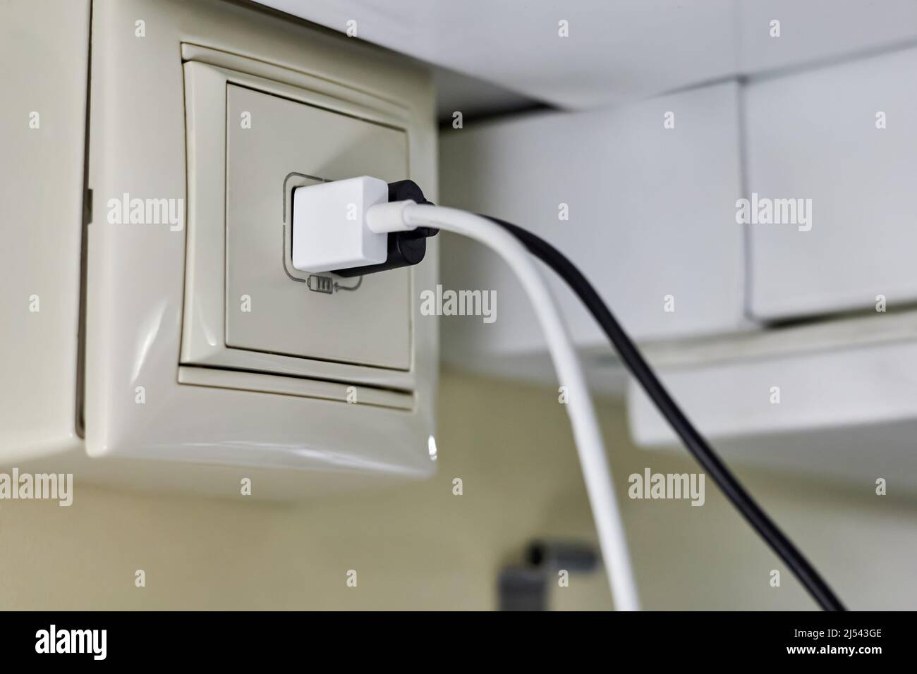 Deux fiches pour charger les smartphones sont insérées dans une prise de chargeur spéciale dans un wagon-compartiment d'un train de voyageurs Banque D'Images