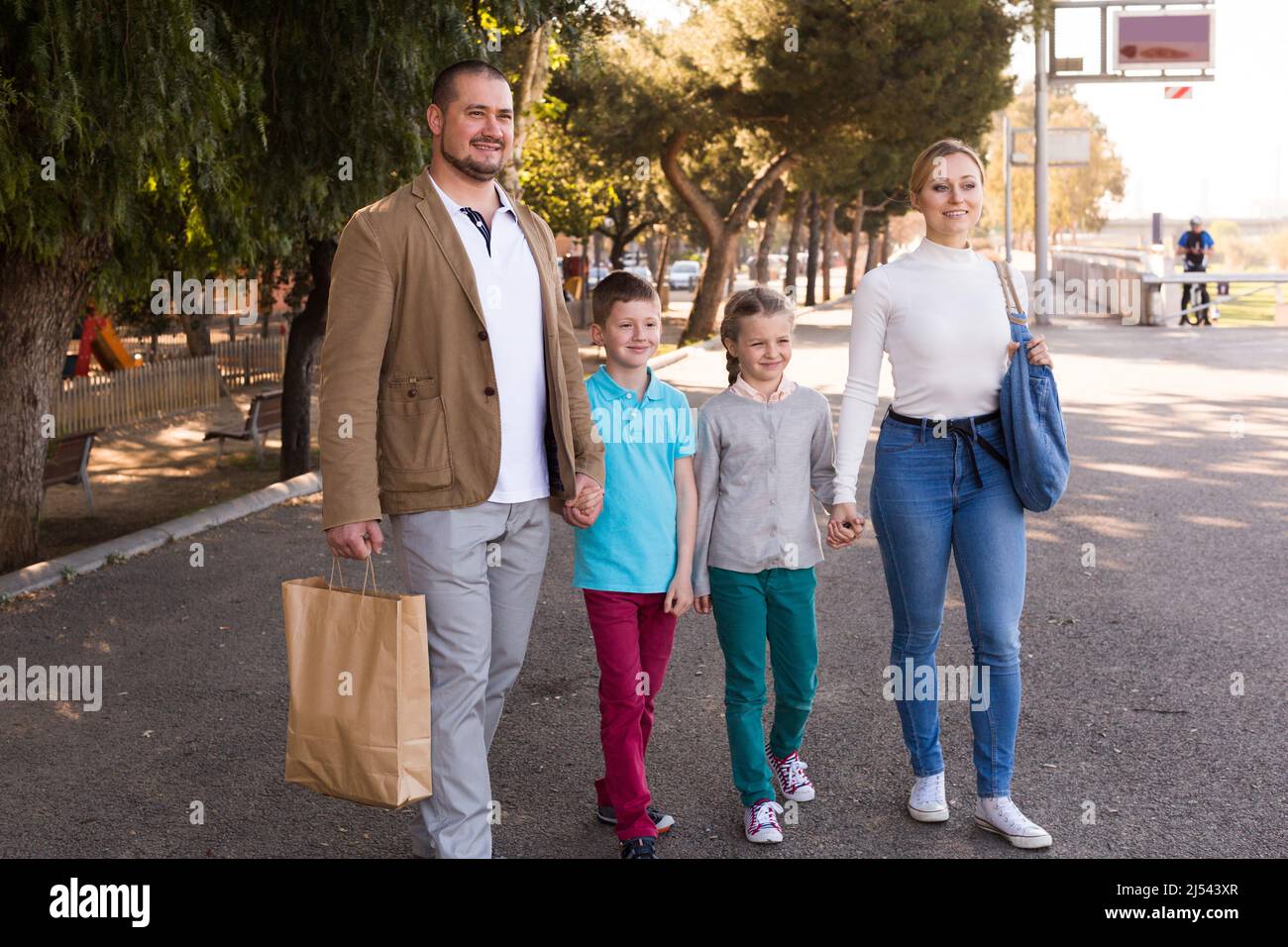 jeunes parents avec deux enfants qui marchent dans la rue Banque D'Images