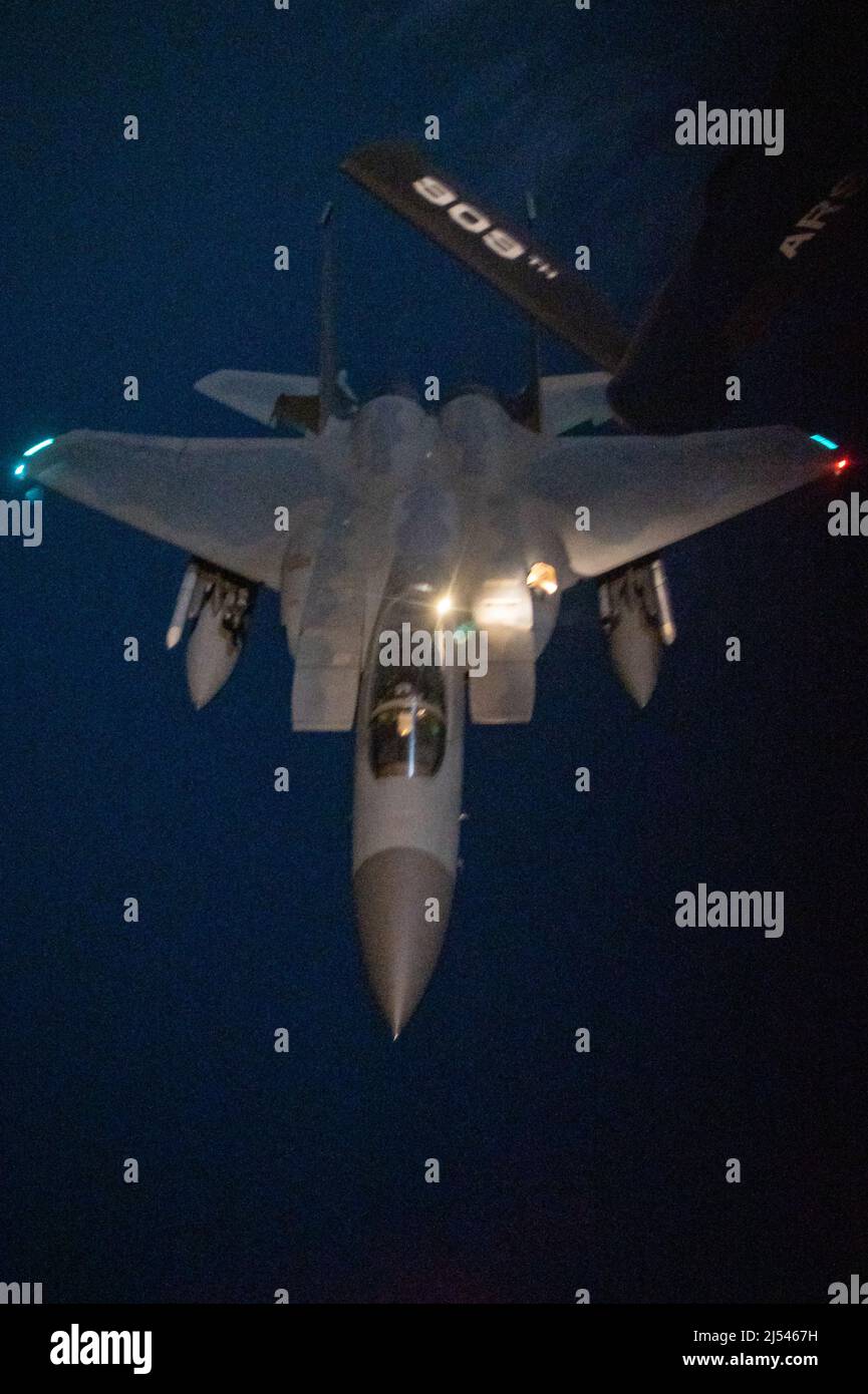 Un escadrille F-15C Eagle du 44th Escadron de chasseurs s'approche d'un escadron de ravitaillement aérien KC-135 Stratotanker pour un ravitaillement aérien la nuit au-dessus de l'océan Pacifique, le 14 avril 909th 2022. Le ravitaillement en vol de nuit est une capacité essentielle pour Kadena, permettant aux avions de chasse de rester en vol plus longtemps et de commander le ciel à tout moment. (É.-U. Photo de la Force aérienne par Airman 1st classe Cesar J. Navarro) Banque D'Images