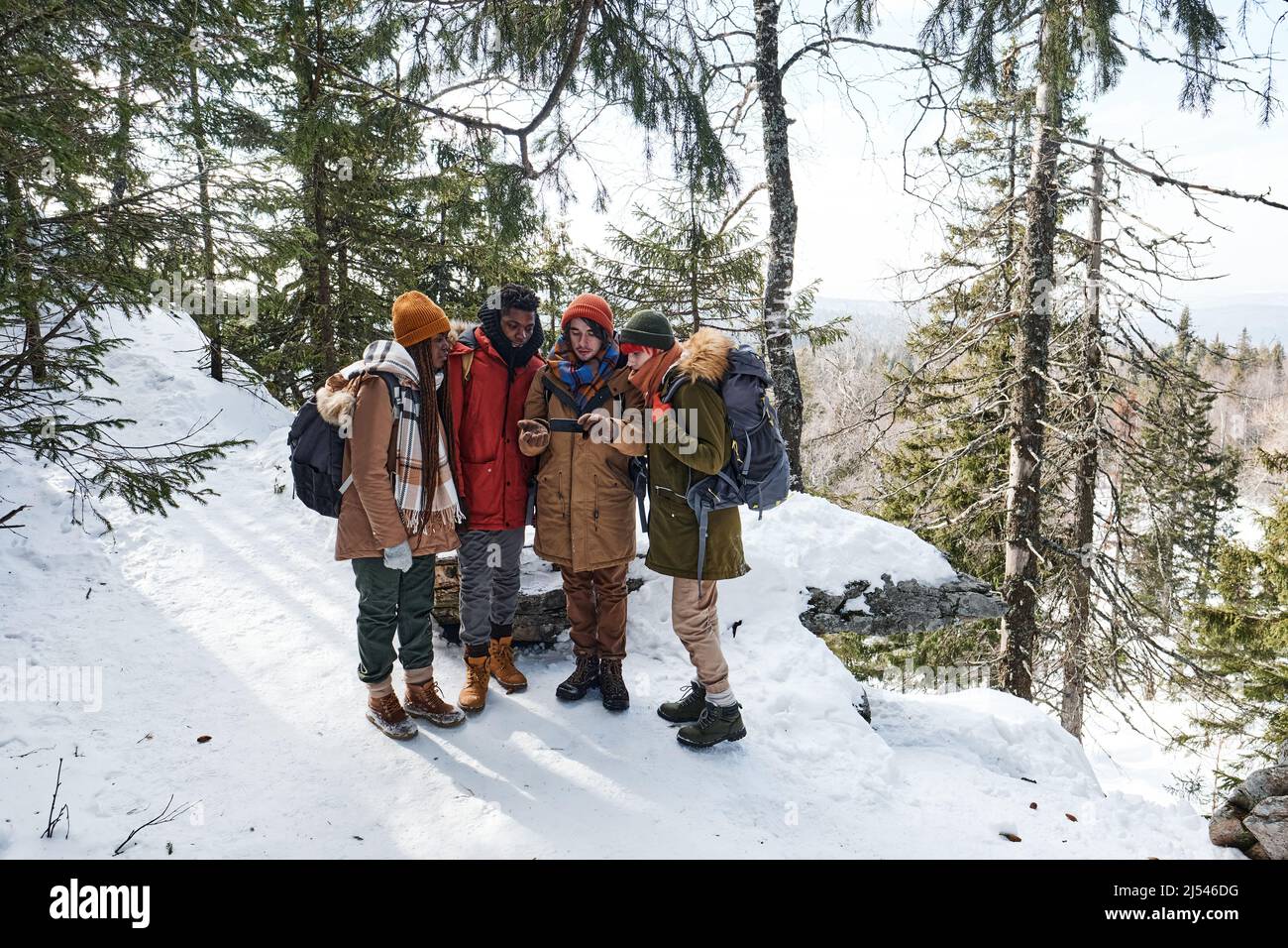 Vue en grand angle prise de vue en grand angle de jeunes amis multi-ethniques qui se rassemblent en montagne en choisissant un itinéraire à l'aide de l'application de carte sur smartphone Banque D'Images