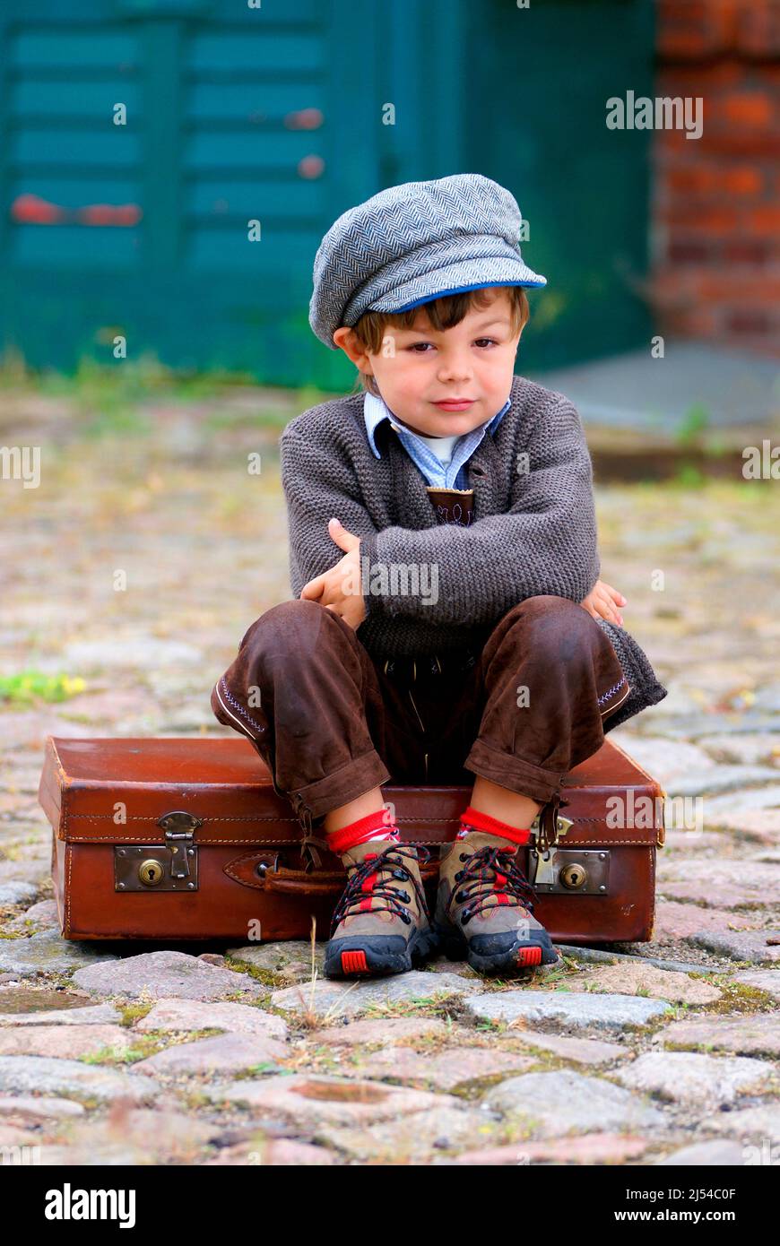 Petit garçon malheureusement assis sur une valise en cuir, Allemagne Banque D'Images