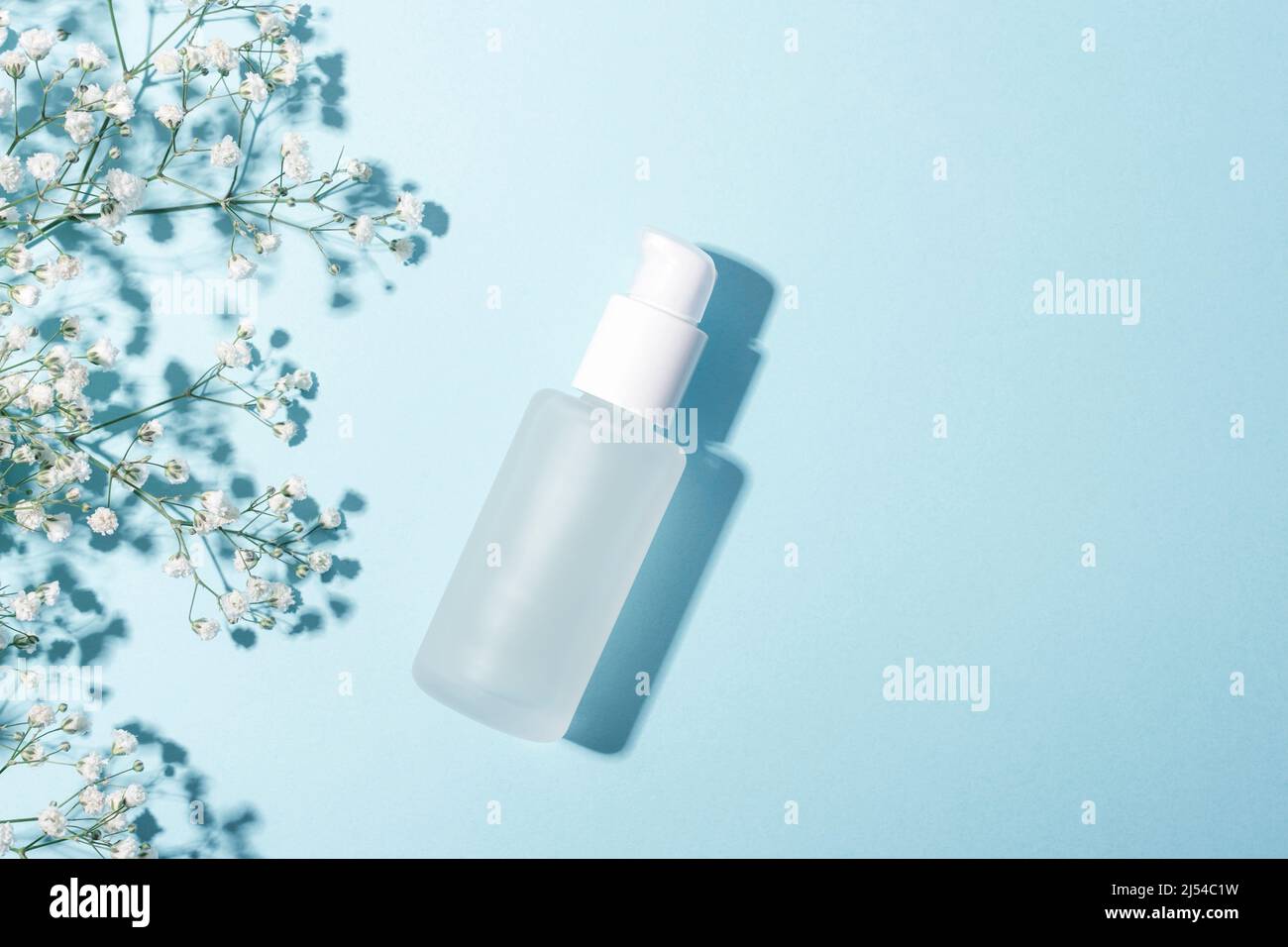 Flacon de sérum sur fond bleu clair avec fleurs de sophila blanches. Médecine alternative, produit de soins de beauté pour la peau. Vue de dessus, plat, espace de copie Banque D'Images