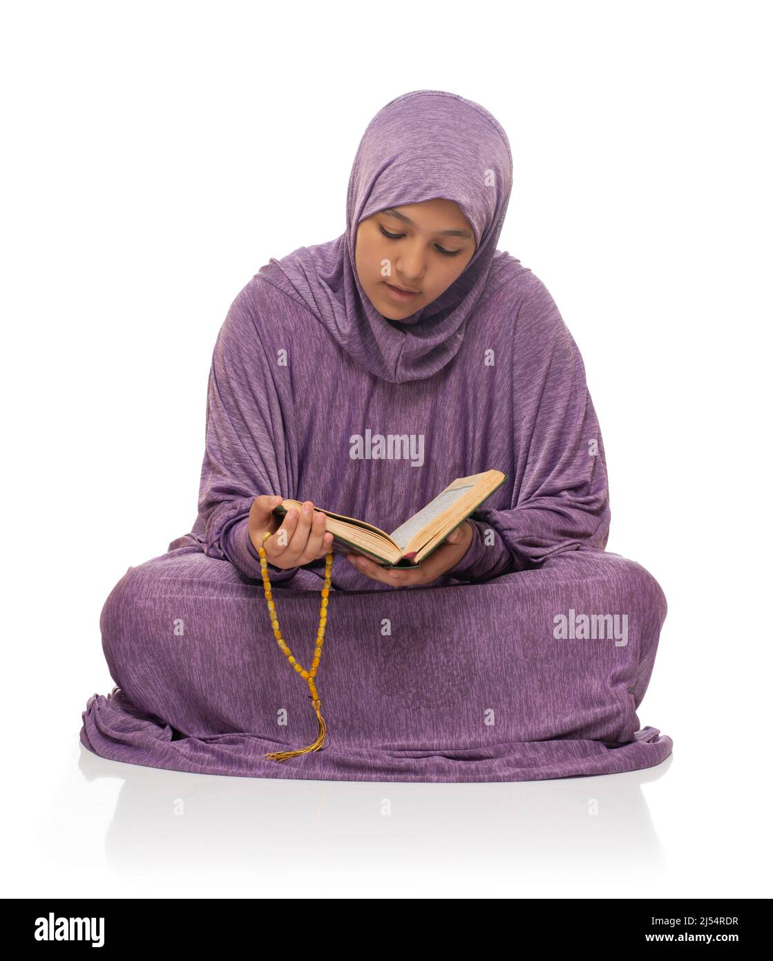 Belle fille musulmane dans la mode islamique Robe assise lisant le livre Saint de Coran , isolé sur fond blanc Banque D'Images