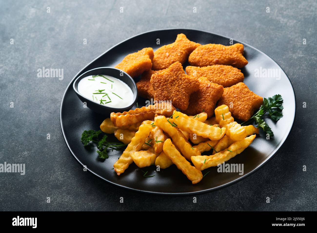 Fish Chips, restauration rapide britannique. Bâtonnets de poisson avec frites sur plaque noire sur fond de table noire. Cuisine traditionnelle britannique authentique ou Banque D'Images