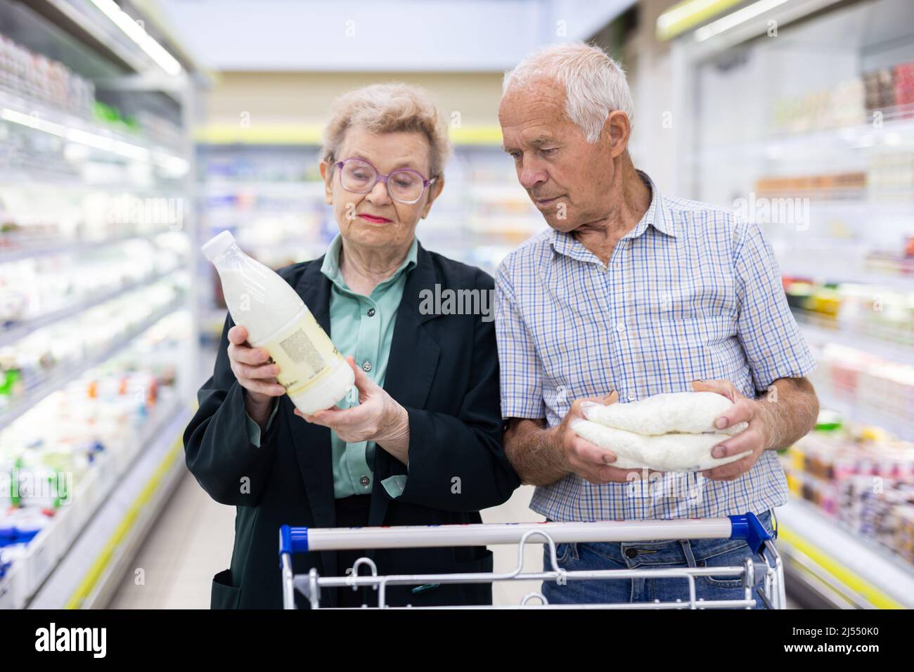 les conjoints caucasiens matures choisissent le lait et le fromage cottage dans la section des produits laitiers du supermarché Banque D'Images