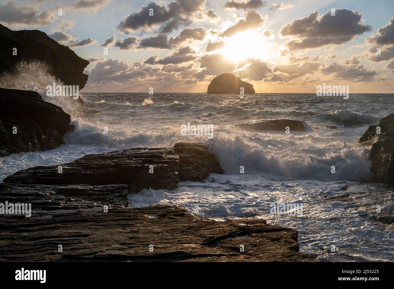 Mer de tempête au coucher du soleil à Trebarwith Strand, nord de Cornwall au Royaume-Uni, avec l'île de Gull Rock, des falaises et des jets de mer. Banque D'Images