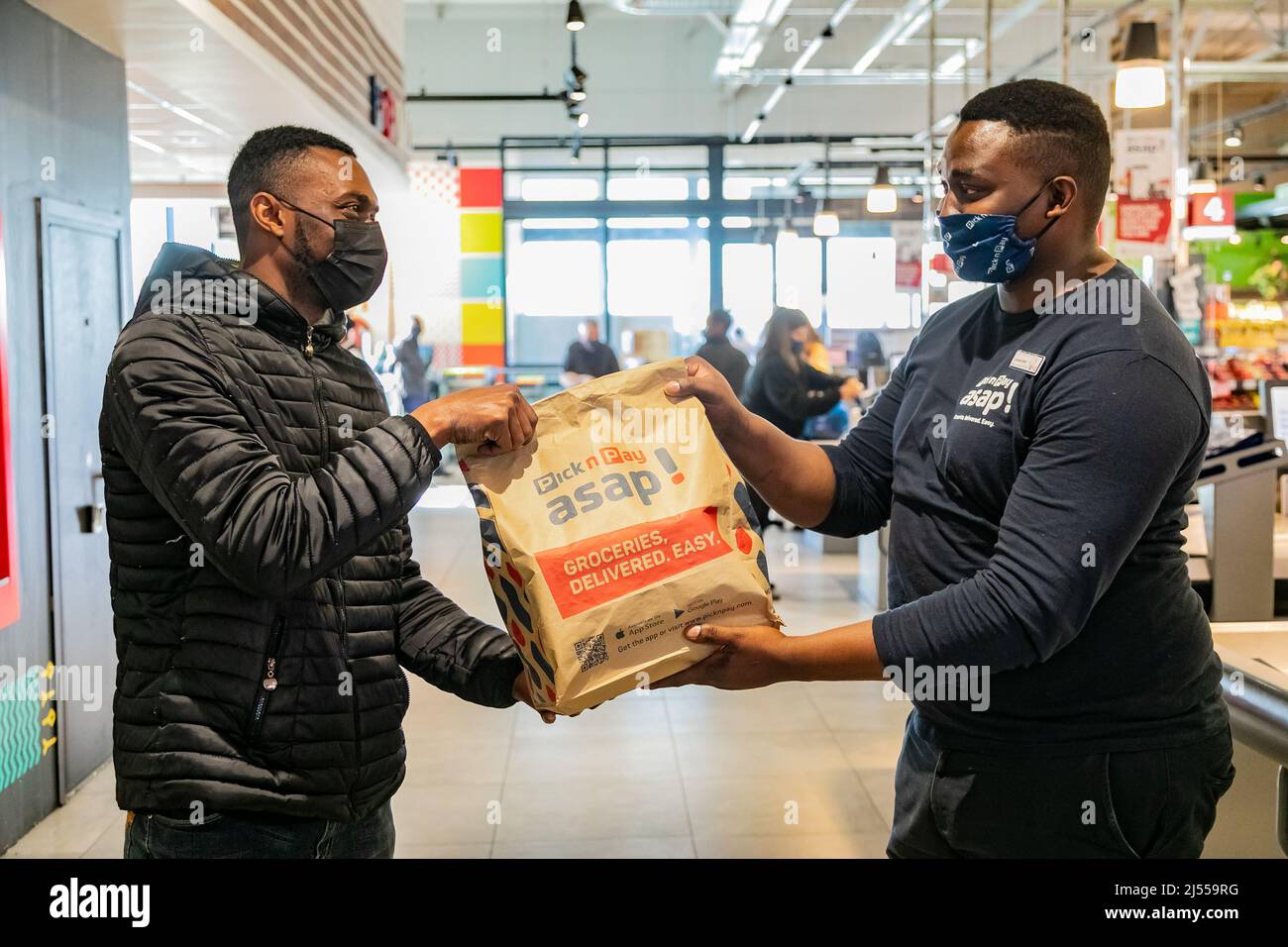 Cape Town, Afrique du Sud - 9 septembre 2021 : le livreur Express Service collecte la commande auprès du personnel au comptoir à l'intérieur de l'épicerie locale Pick n Pay Banque D'Images