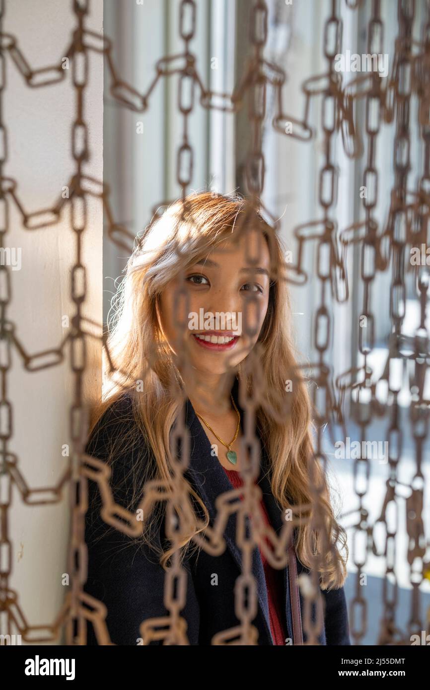 Jeune femme asiatique debout derrière la barrière de chaîne au ferry de San Francisco Breezeway | Portrait de style de vie Banque D'Images