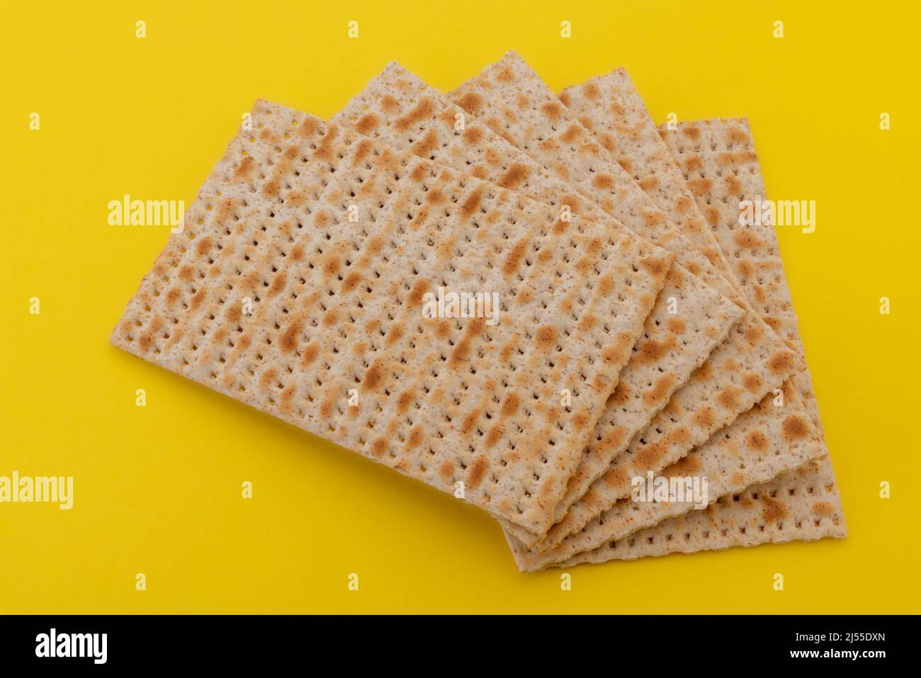 Matzo pain sans levain pour Pesach, fête juive de la Pâque. Pains plats Matzah isolés sur fond jaune. Banque D'Images