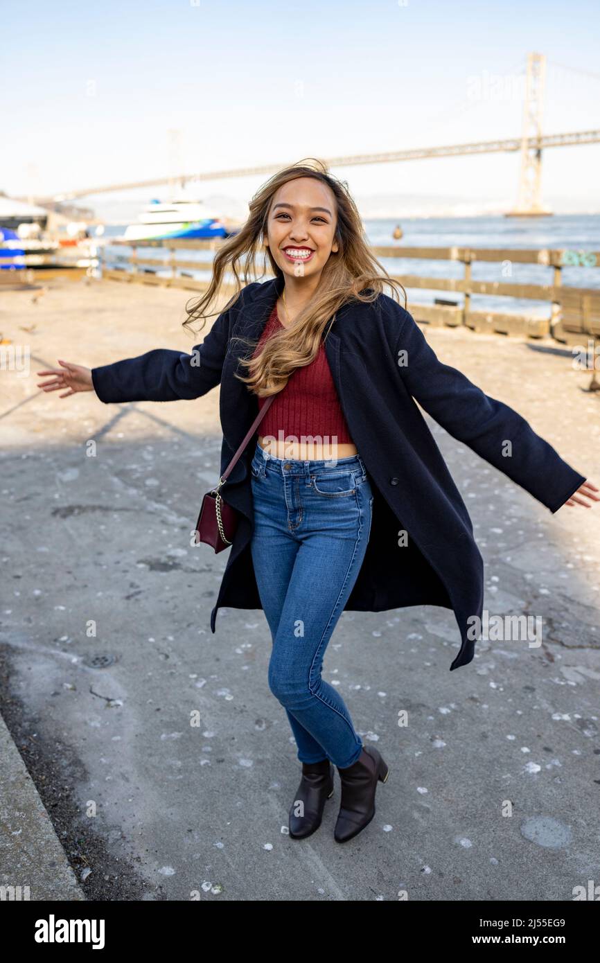 Jeune femme dansant avec joie sur l embarcadere avec le pont de la baie d Oakland en arriere plan Lifestyle local Tourism Photo Stock Alamy